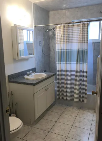 a bathroom with a granite countertop sink a toilet and shower