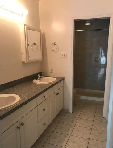 a bathroom with a granite countertop sink a mirror and a shower