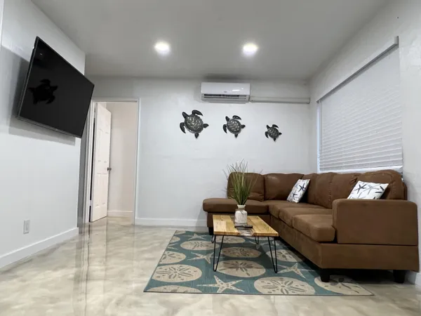 a living room with furniture a flat screen tv and kitchen view