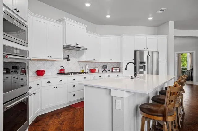 a kitchen with white cabinets a sink stove and white refrigerator