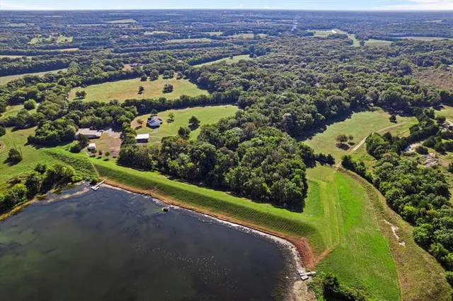 an aerial view of a residential houses with a yard and lake view in back