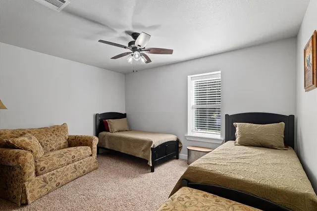 a bedroom with two beds and ceiling fan