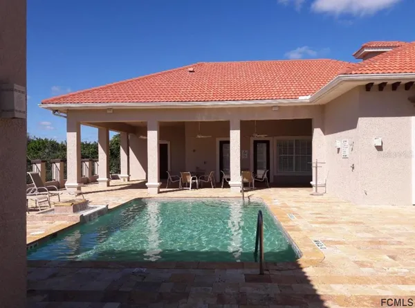 a view of swimming pool with lawn chairs and iron fence