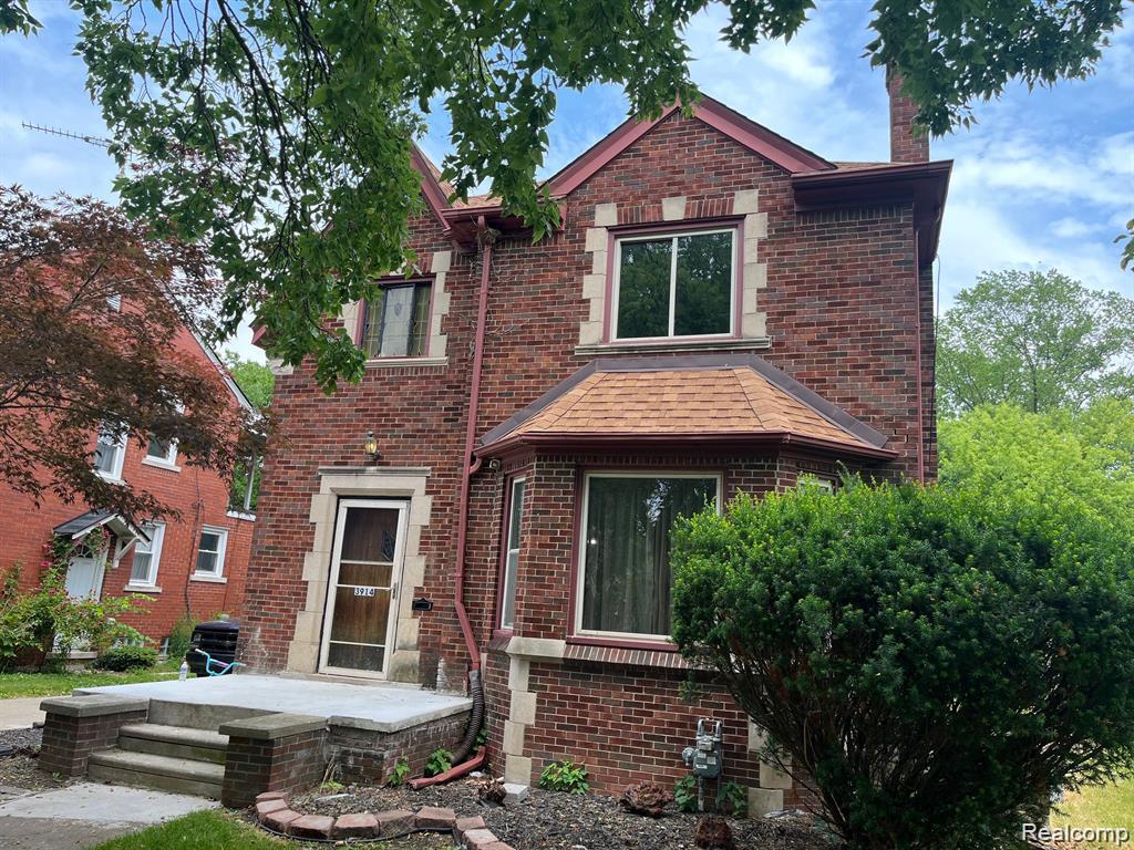 3914 Balfour Road Detroit, MI 48224 - Photo 2 of 24 Brick exterior with stone accents, bay window with shingle roof, concrete porch, and mature landscaping