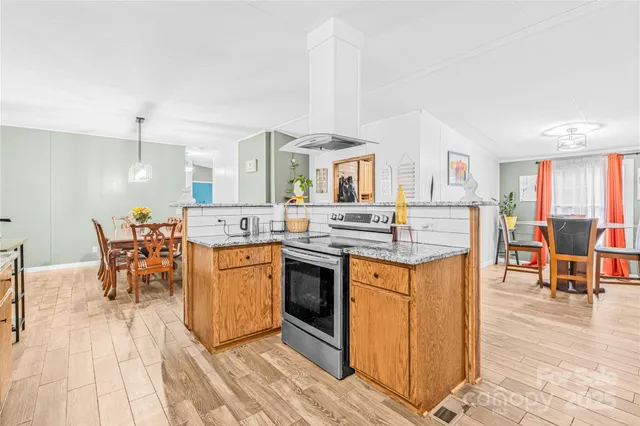 a kitchen with stainless steel appliances granite countertop a stove top oven a sink a dining table and chairs