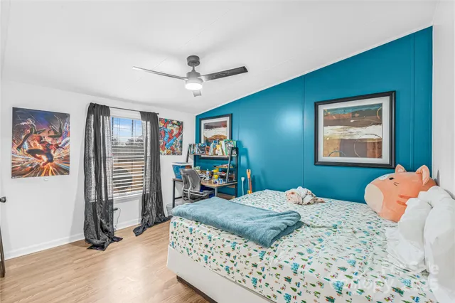 a bedroom with a bed dresser and wooden floor
