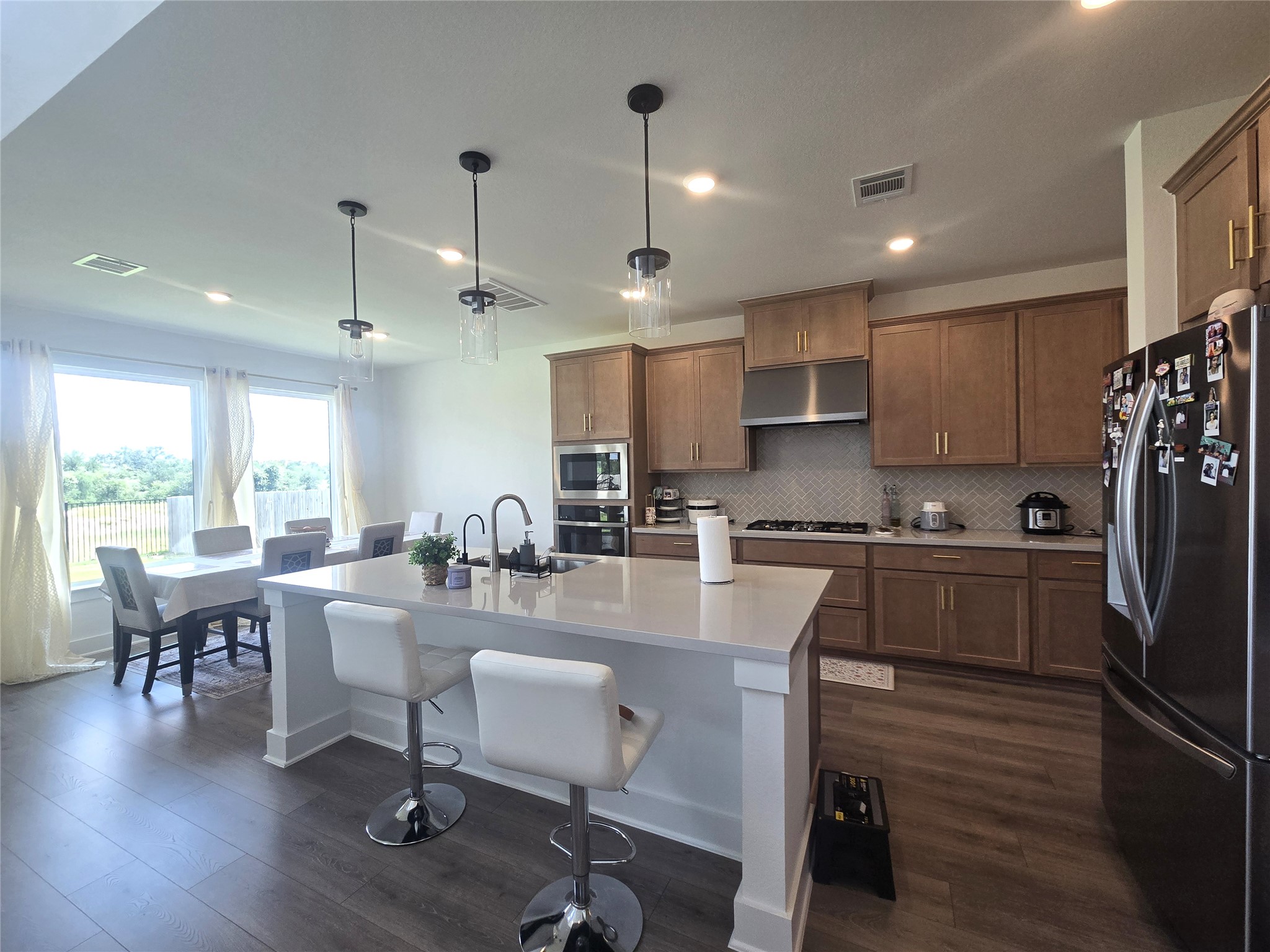 124 Ribera Drive Liberty Hill, TX 78642 - Photo 10 of 40 An open-concept design connects the functional kitchen with a relaxed dining area, illuminated by bright pendant lights.