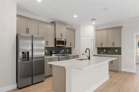 a kitchen with stainless steel appliances granite countertop a sink a stove and a wooden floors