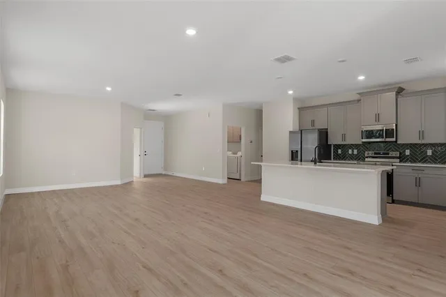 a kitchen with stainless steel appliances kitchen island granite countertop a sink a stove a refrigerator and cabinets