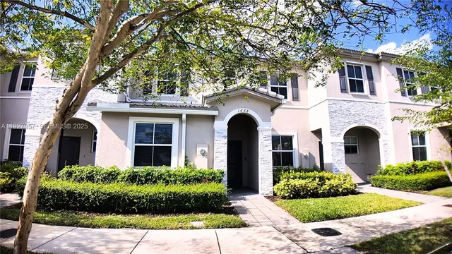 a front view of a house with garden and trees