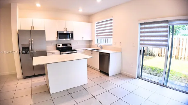 a kitchen with stainless steel appliances granite countertop a stove a sink a microwave a refrigerator and cabinets