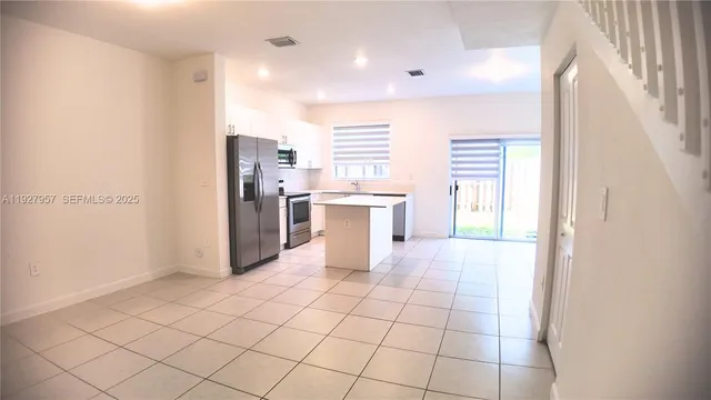 a large white kitchen with a sink and dishwasher a refrigerator with wooden floor