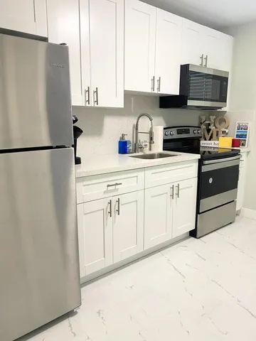 a kitchen with stainless steel appliances white cabinets and a refrigerator