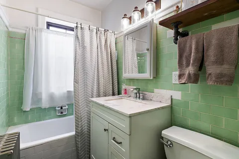 a bathroom with a sink a toilet a mirror and shower