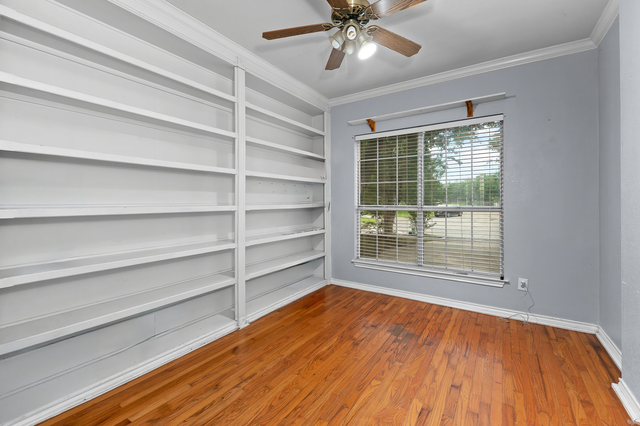 11737 Rydalwater Lane Austin, TX 78754 - Photo 8 of 40 Room featuring extensive built-in shelving, wood-finish flooring, and a large window with horizontal blinds