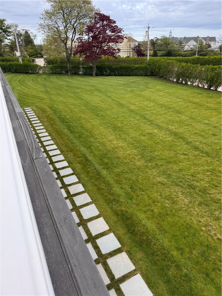 150 Boston Neck Road Narragansett, RI 02882 - Photo 49 of 50 Pavers lining the front of the home next to screened in patio & spacious yard with a thick row of hedges along the property for privacy