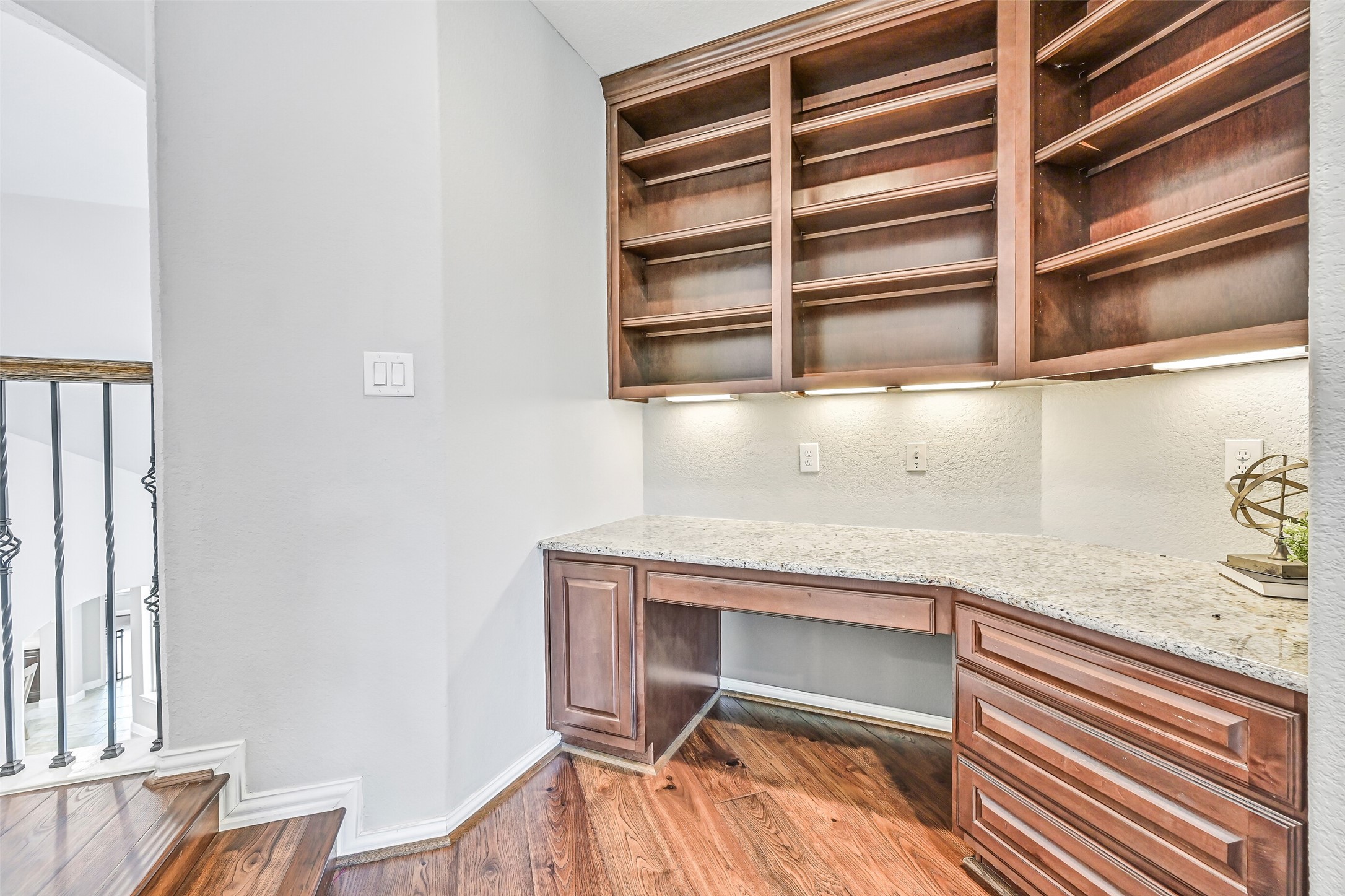 1008 Point Isabel Lane Friendswood, TX 77546 - Photo 35 of 50 A custom built-in workspace features stained cabinetry, granite countertops, upper display shelving, and under cabinet lighting. Ideal for a home office or homework station, this space blends function with a clean, built-in design.
