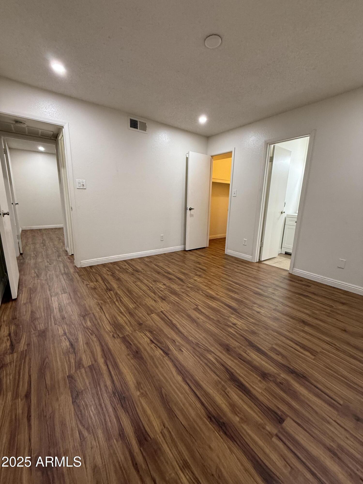 3033 North 37th Street, Unit 12 Phoenix, AZ 85018 - Photo 5 of 11 an empty room with wooden floor and mirror