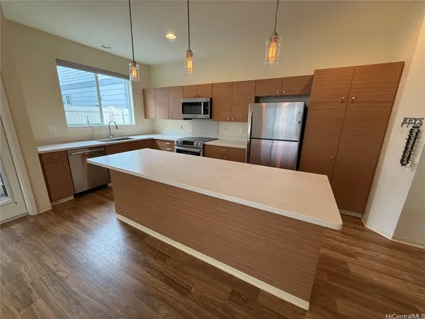 a large kitchen with stainless steel appliances a large counter top a sink a refrigerator and window