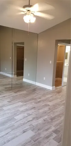 en empty room with wooden floor and fan