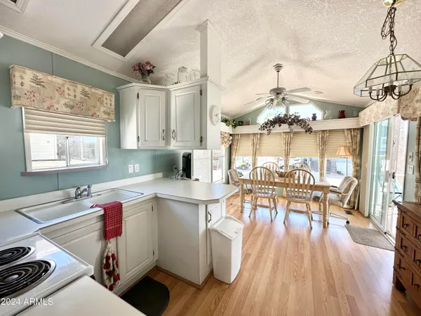 a open kitchen with stainless steel appliances granite countertop a stove top oven a dining table and chairs with wooden floor