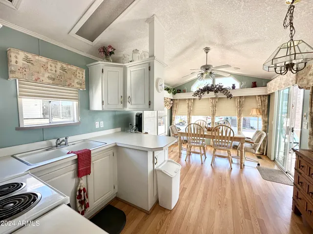 a open kitchen with stainless steel appliances granite countertop a stove top oven a dining table and chairs with wooden floor