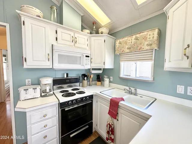 a kitchen with granite countertop a sink cabinets stainless steel appliances and a window