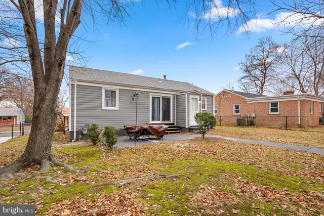 a backyard of a house with table and chairs under an umbrella