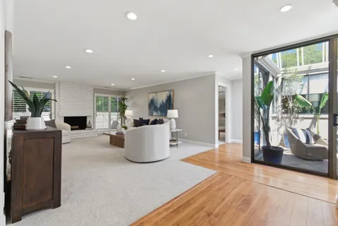 a living room with furniture a floor to ceiling window and potted plants