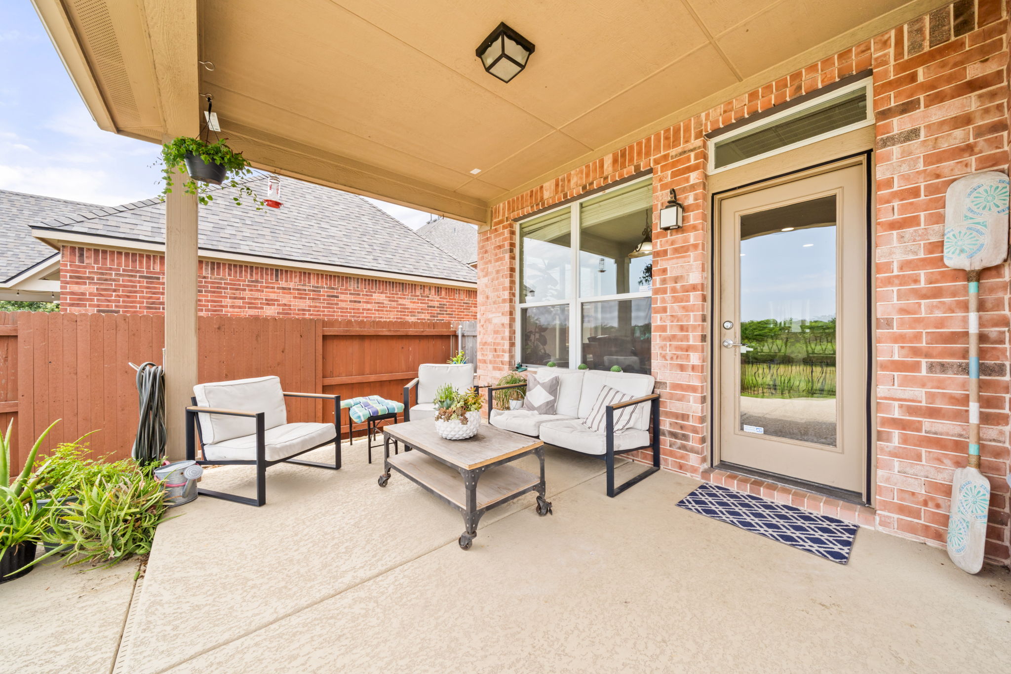 1581 Grassy Field Road Austin, TX 78737 - Photo 32 of 37 A covered concrete patio sits alongside a brick exterior wall and wooden privacy fence.