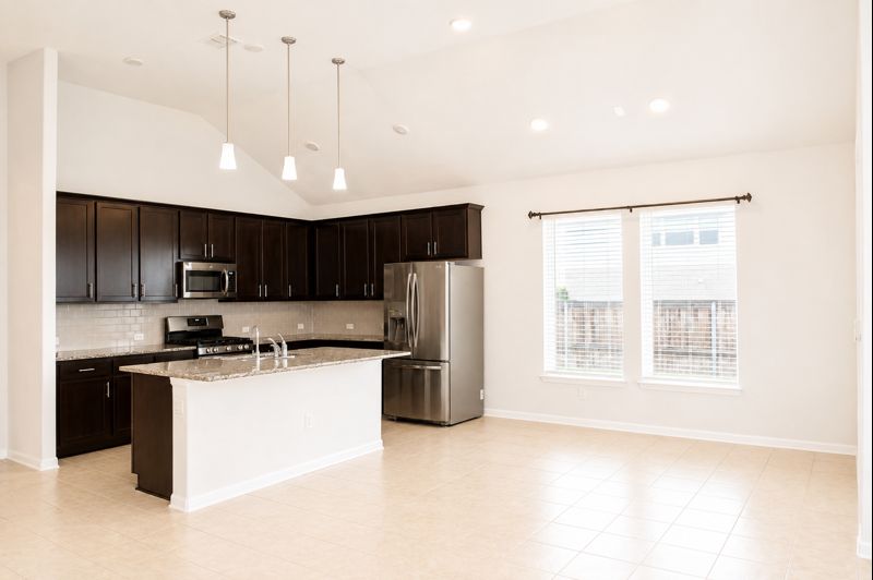 693 Durian Loop Buda, TX 78610 - Photo 7 of 27 Culinary creations come to life in this kitchen featuring an island, granite counters, and vaulted ceilings.