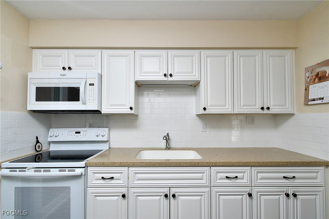 13 Hamlin Court Lehigh Acres, FL 33936 - Photo 10 of 31 a kitchen with white cabinets and white appliances