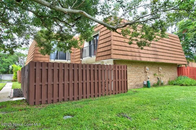 a view of a house with a small yard and a large tree
