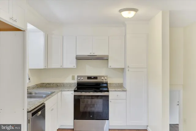 a kitchen with granite countertop white cabinets and stainless steel appliances