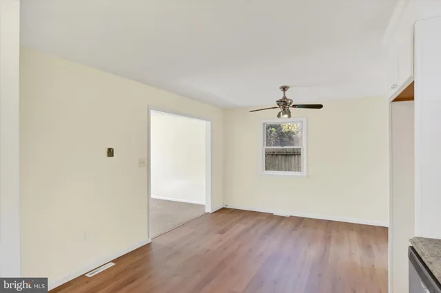 an empty room with wooden floor cabinet and windows