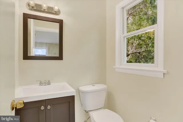 a bathroom with a toilet a sink a window and mirror