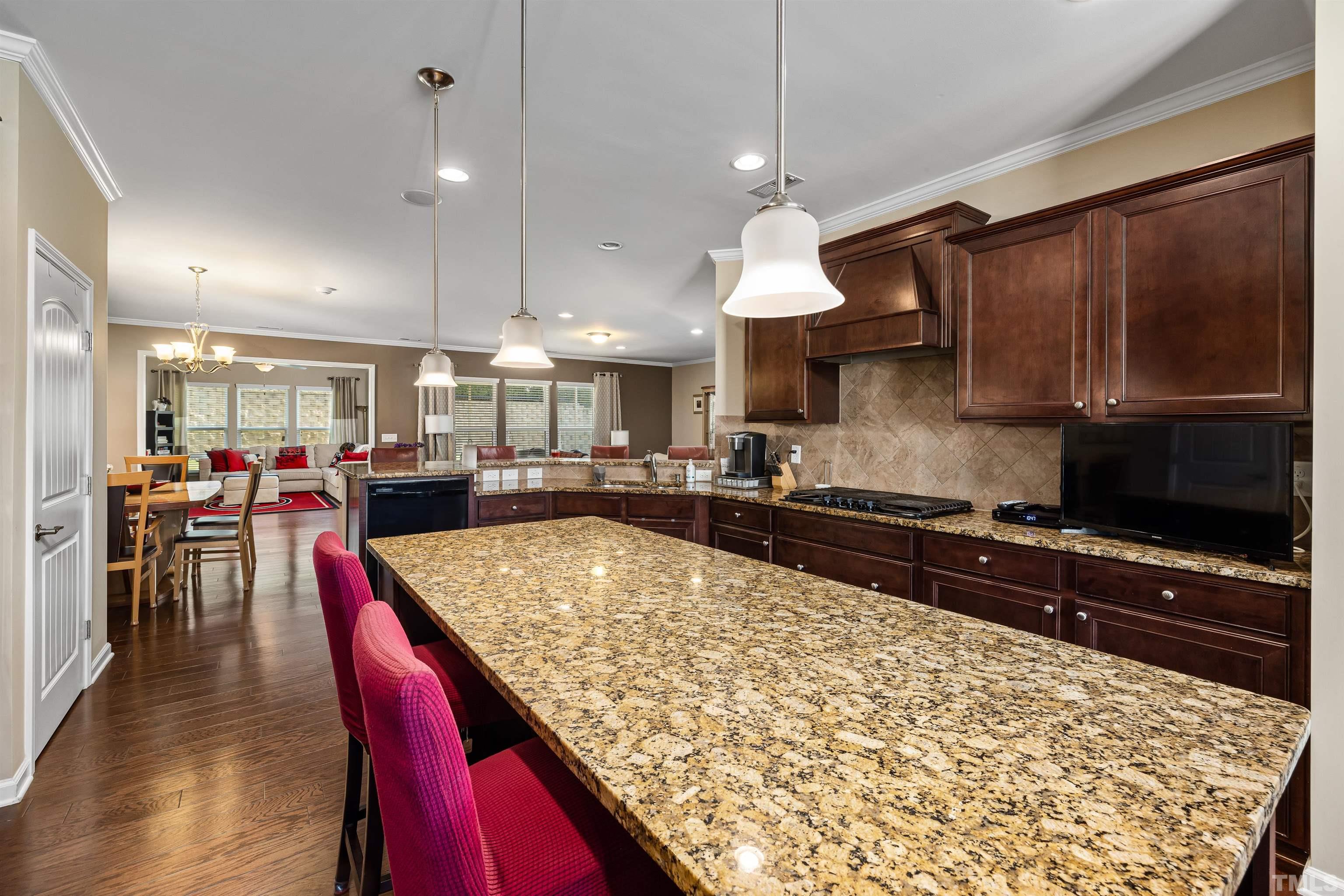 1115 Hooper Place Durham, NC 27703 - Photo 8 of 40 a kitchen with stainless steel appliances granite countertop a stove top oven a sink a dining table and chairs with wooden floor
