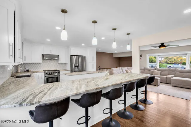 a living room with furniture kitchen view and a wooden floor