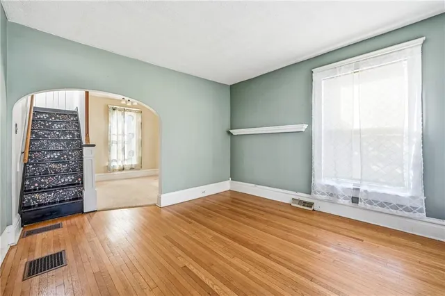 a view of an empty room with window and wooden floor