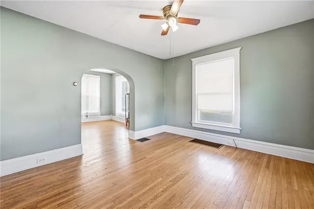 an empty room with wooden floor fan and windows