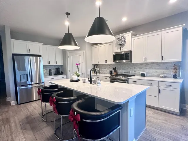 a kitchen with stainless steel appliances granite countertop a sink a stove a refrigerator and island with wooden floor