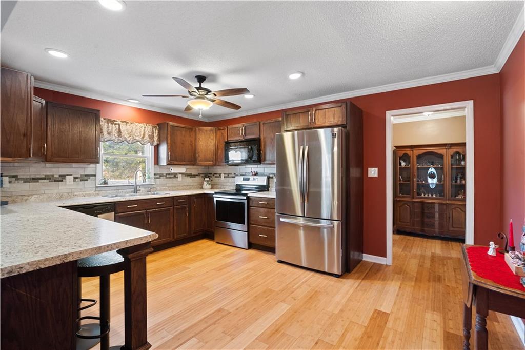 297 Tucker Hollow Road Southeast Calhoun, GA 30701 - Photo 10 of 42 a kitchen with stainless steel appliances granite countertop a refrigerator a sink dishwasher a stove with wooden cabinets and floor