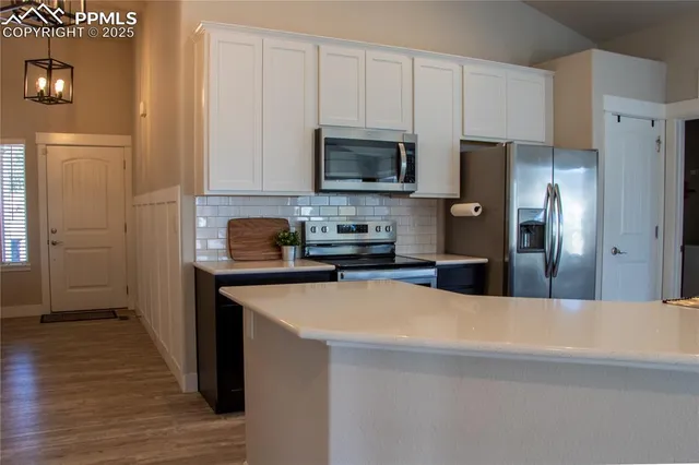 a kitchen with stainless steel appliances a refrigerator a stove a sink and white cabinets