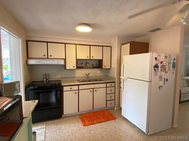 a kitchen with granite countertop a refrigerator stove top oven a sink and dishwasher