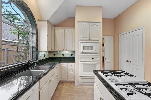 a kitchen with granite countertop a sink stove and cabinets