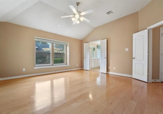 a view of an empty room with a window and wooden floor