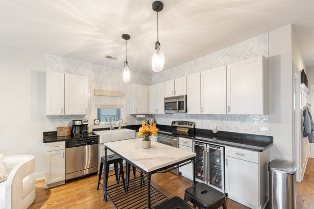 a kitchen with a stove a sink a kitchen island with chairs and wooden floor