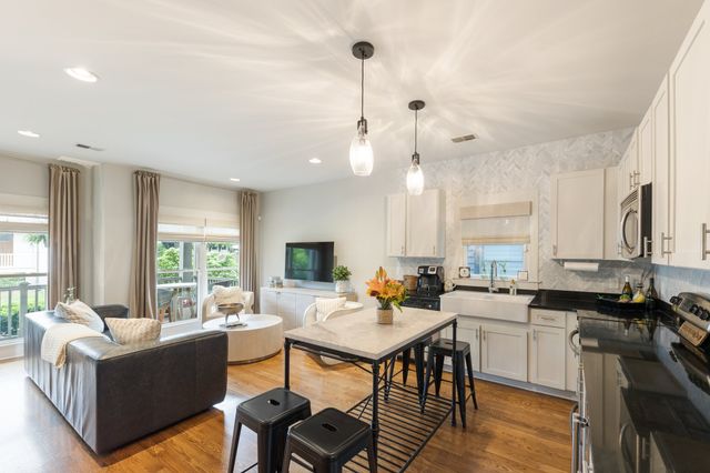 a living room with furniture kitchen area and a large window