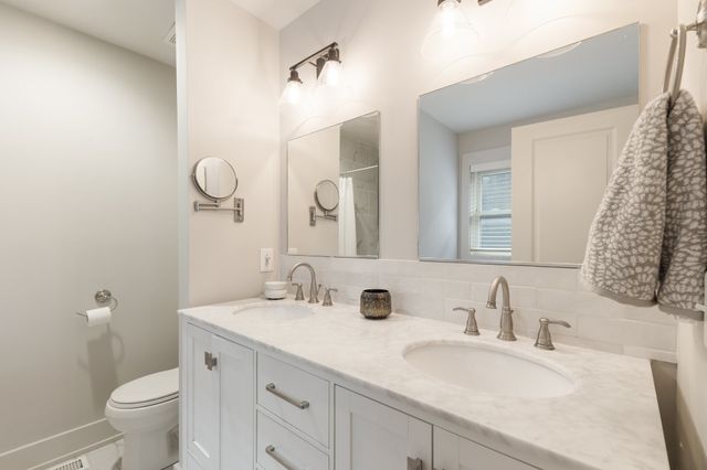 a bathroom with a granite countertop sink a toilet and a mirror