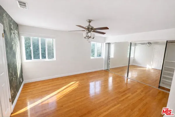 a view of an empty room with a window and wooden floor